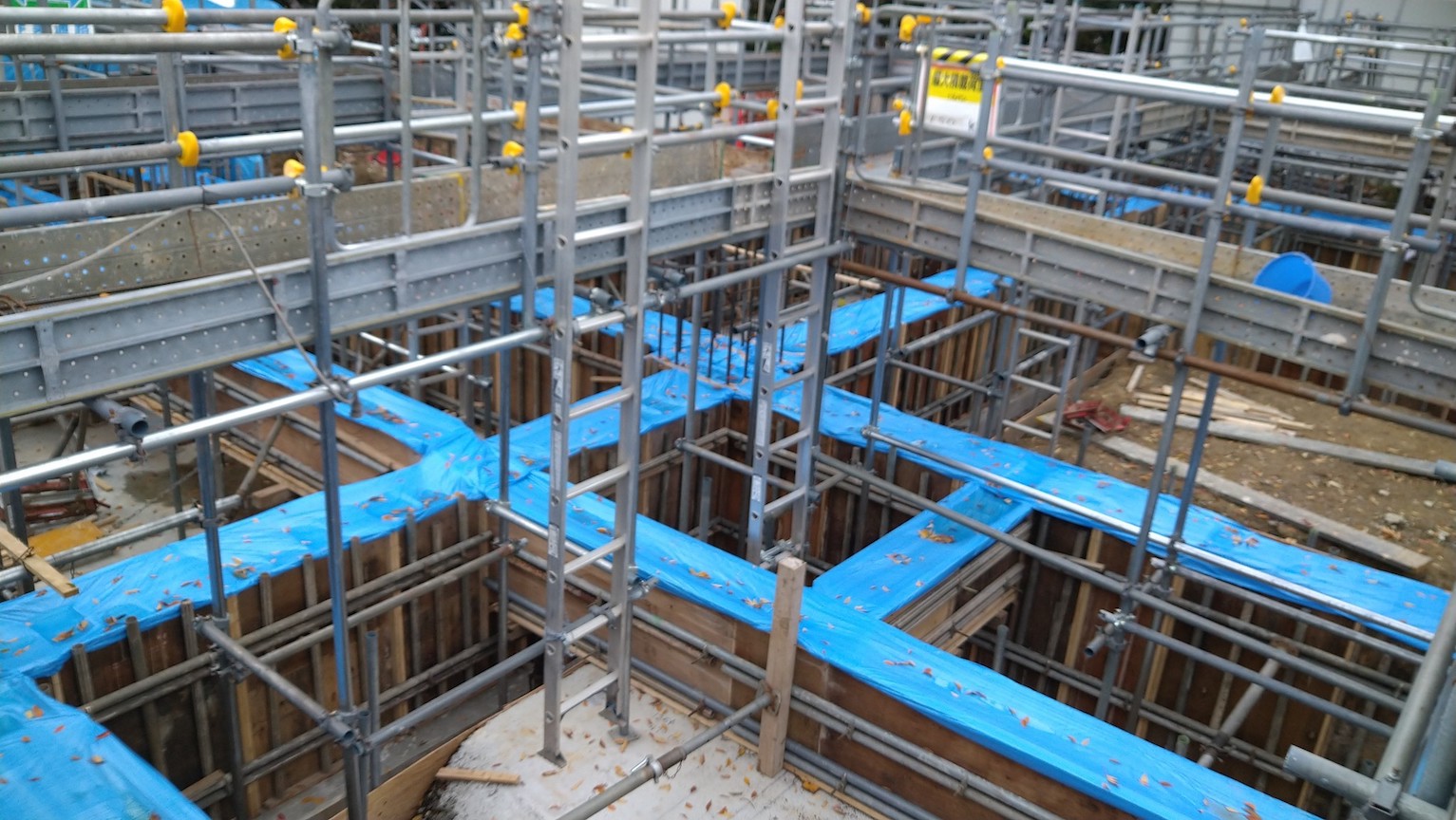 This is the foundation work for Koufu Children's School (children's care facility). The formwork is covered with blue tarpaulin to prevent leaves from falling in.